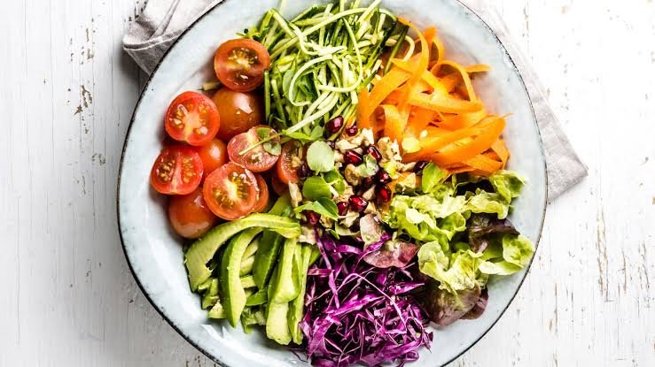 Bowl of raw vegetables with tomatoes, avocado, red cabbage and zucchini noodles