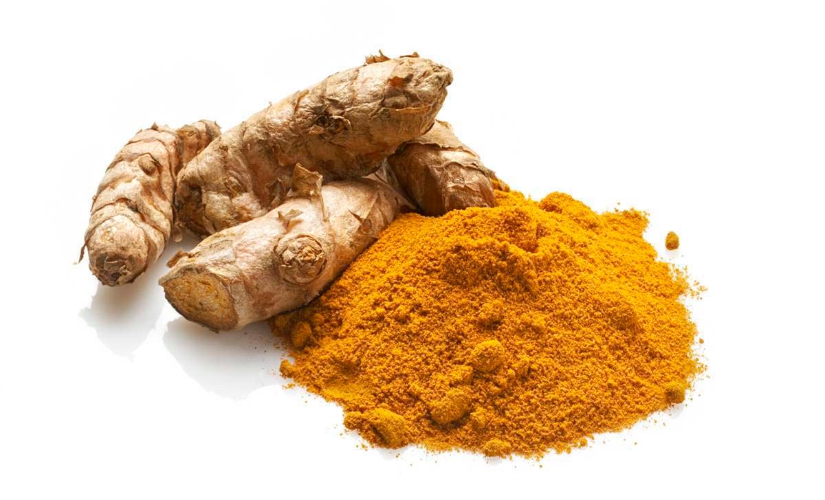 Fresh turmeric root next to a pile of ground turmeric powder