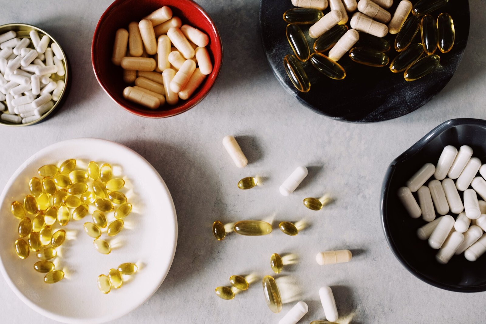 Vitamin capsules and softgel supplements in small bowls