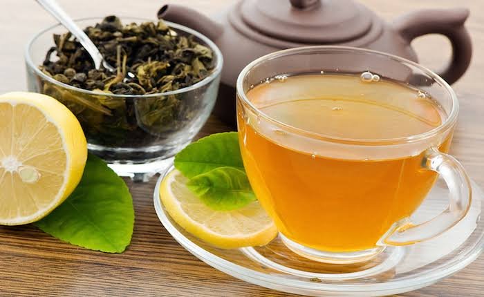 Cup of green tea with lemon and loose tea leaves