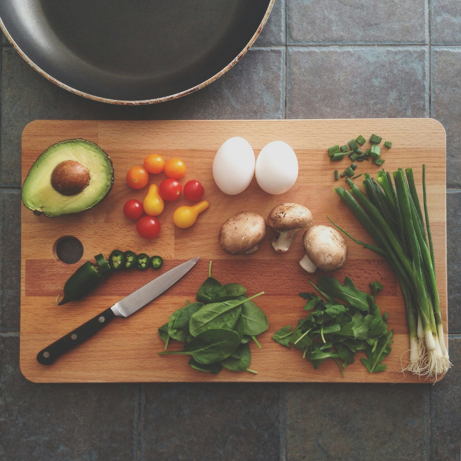Iron-rich foods for anemia: eggs, spinach, mushrooms, avocado and fresh vegetables on a wooden board